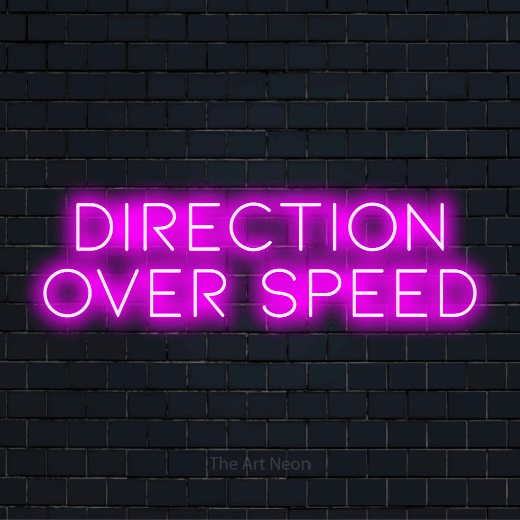 "Direction Over Speed" LED neon sign on a black brick wall