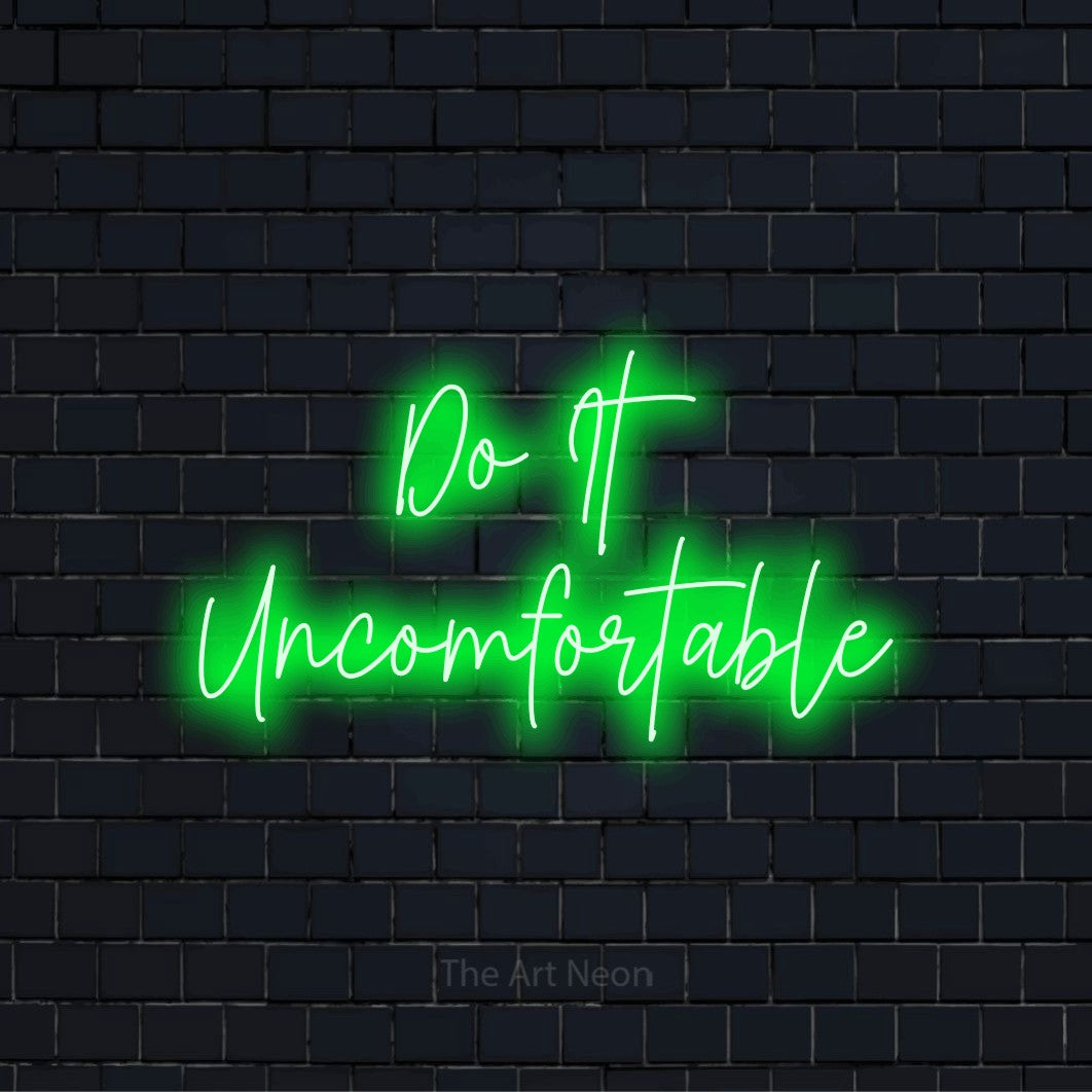 "Do It Uncomfortable" neon text design on a black brick wall