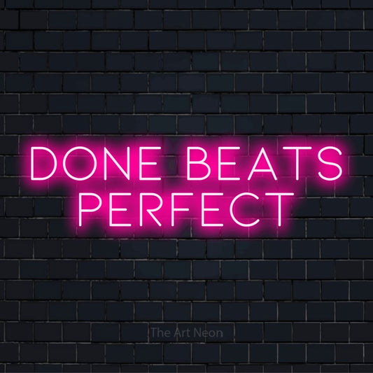 "Done Beats Perfect" script-style LED neon sign on a black brick wall