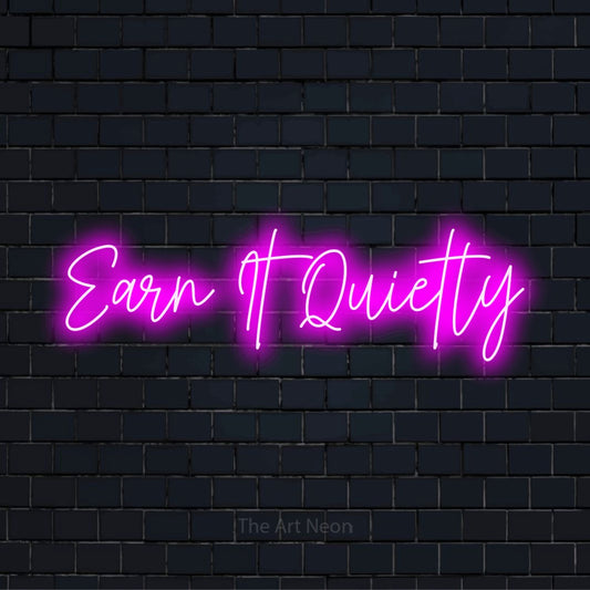 "Earn It Quietly" script-style LED neon sign on a black brick wall