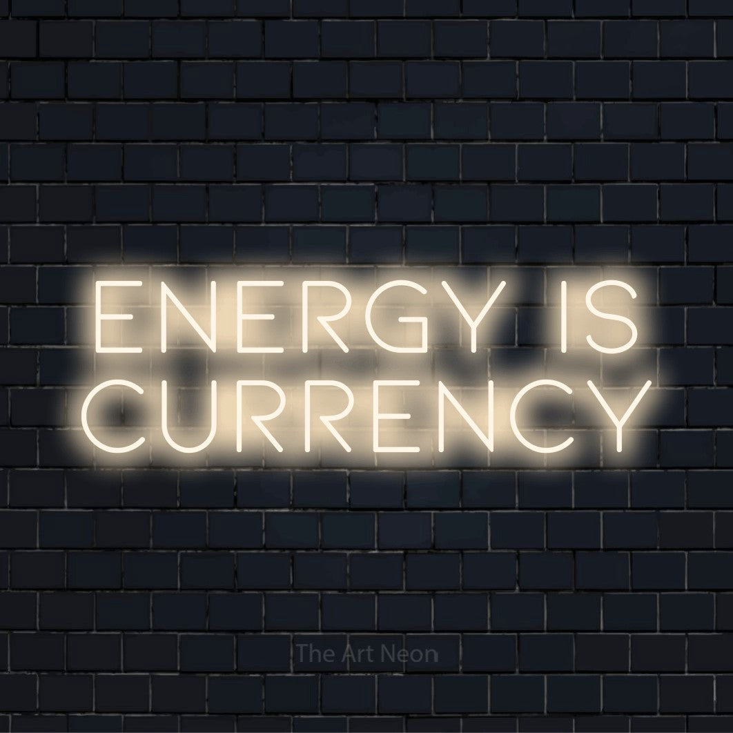 "Energy Is Currency" script-style LED neon sign on a black brick wall