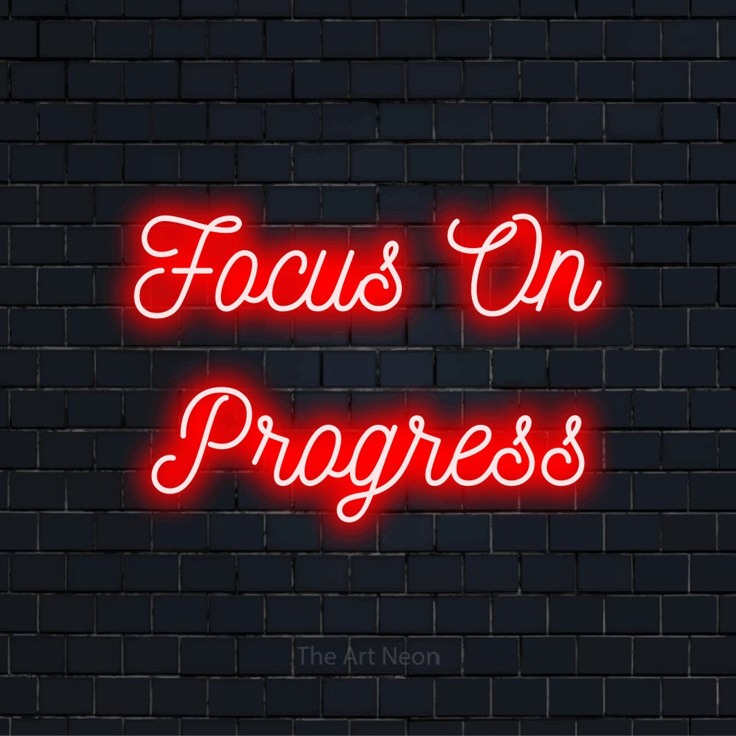 "Focus On Progress" text design with neon effect on a black brick wall