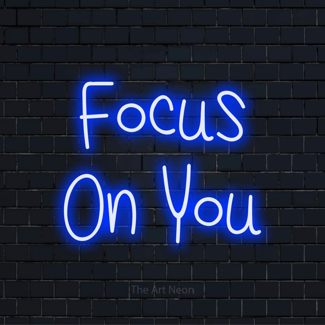 "Focus On You" script-style LED neon sign on a black brick wall
