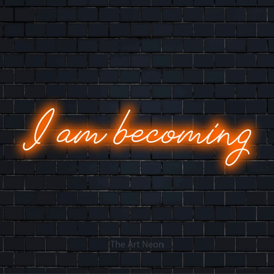 "I Am Becoming" script-style LED neon sign on a black brick wall