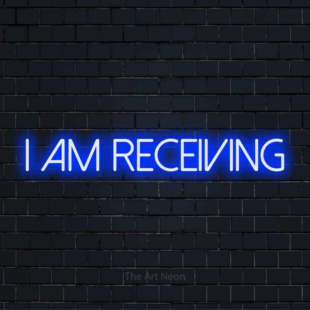 "I Am Receiving" script-style LED neon sign on a black brick wall