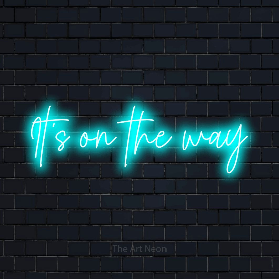 "It’s On The Way" LED neon sign on a black brick wall