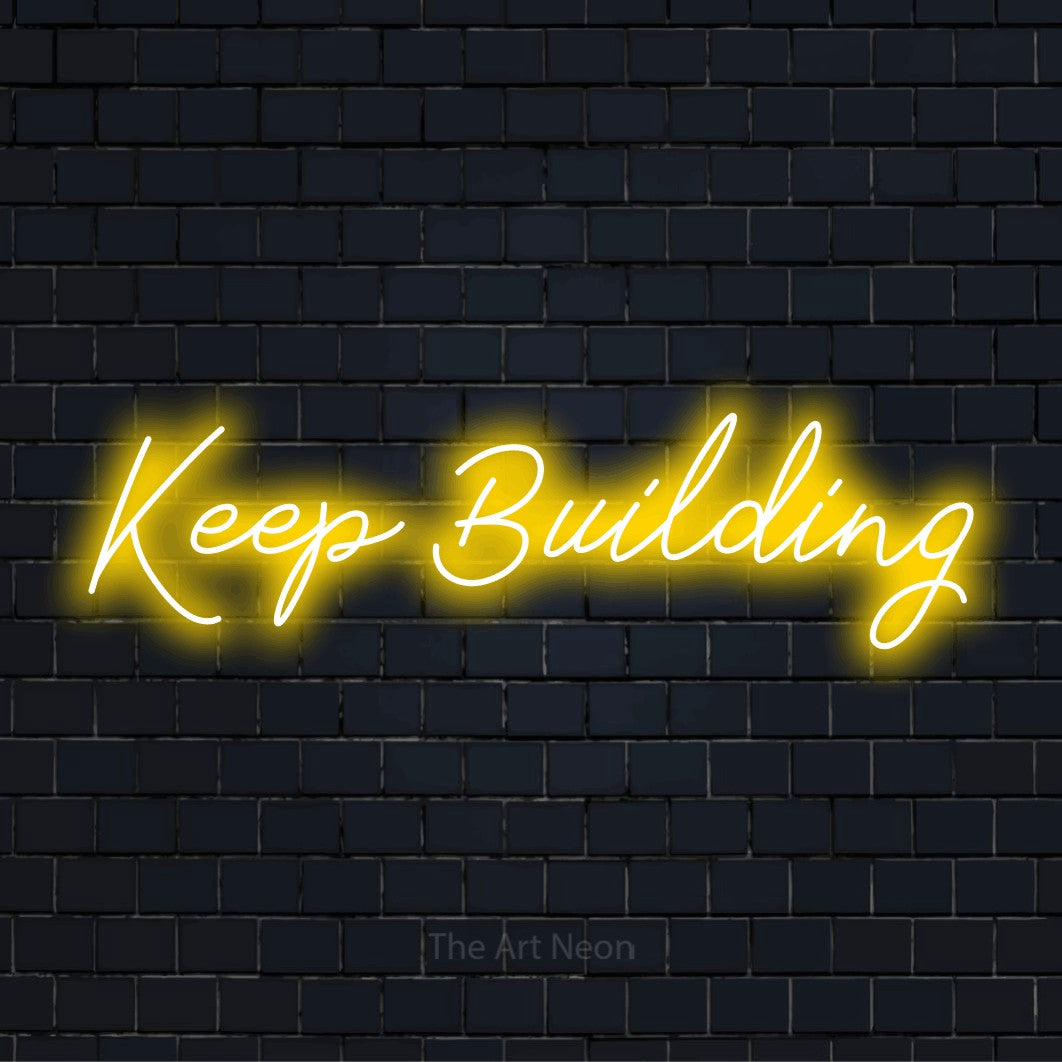"Keep Building" neon text design on a black brick wall