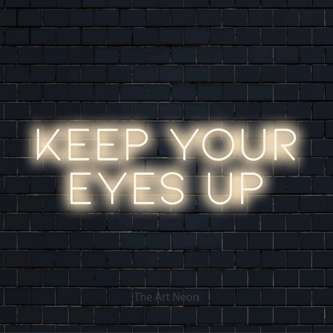 "Keep Your Eyes Up" LED neon sign on a black brick wall