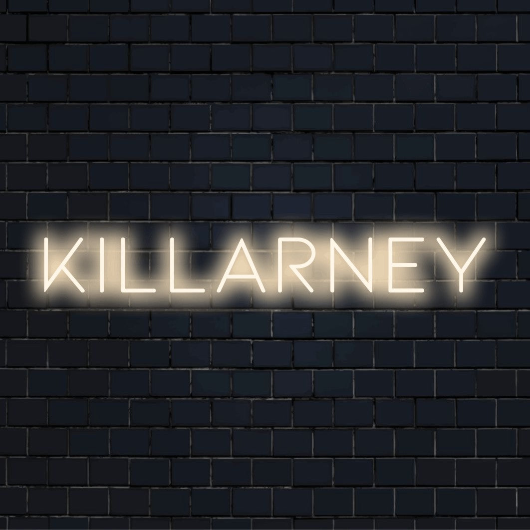 Killarney LED Neon Sign, glowing lettering against black brick wall