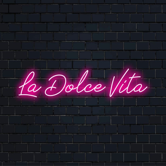 La Dolce Vita Neon Light with glowing lettering against black brick wall