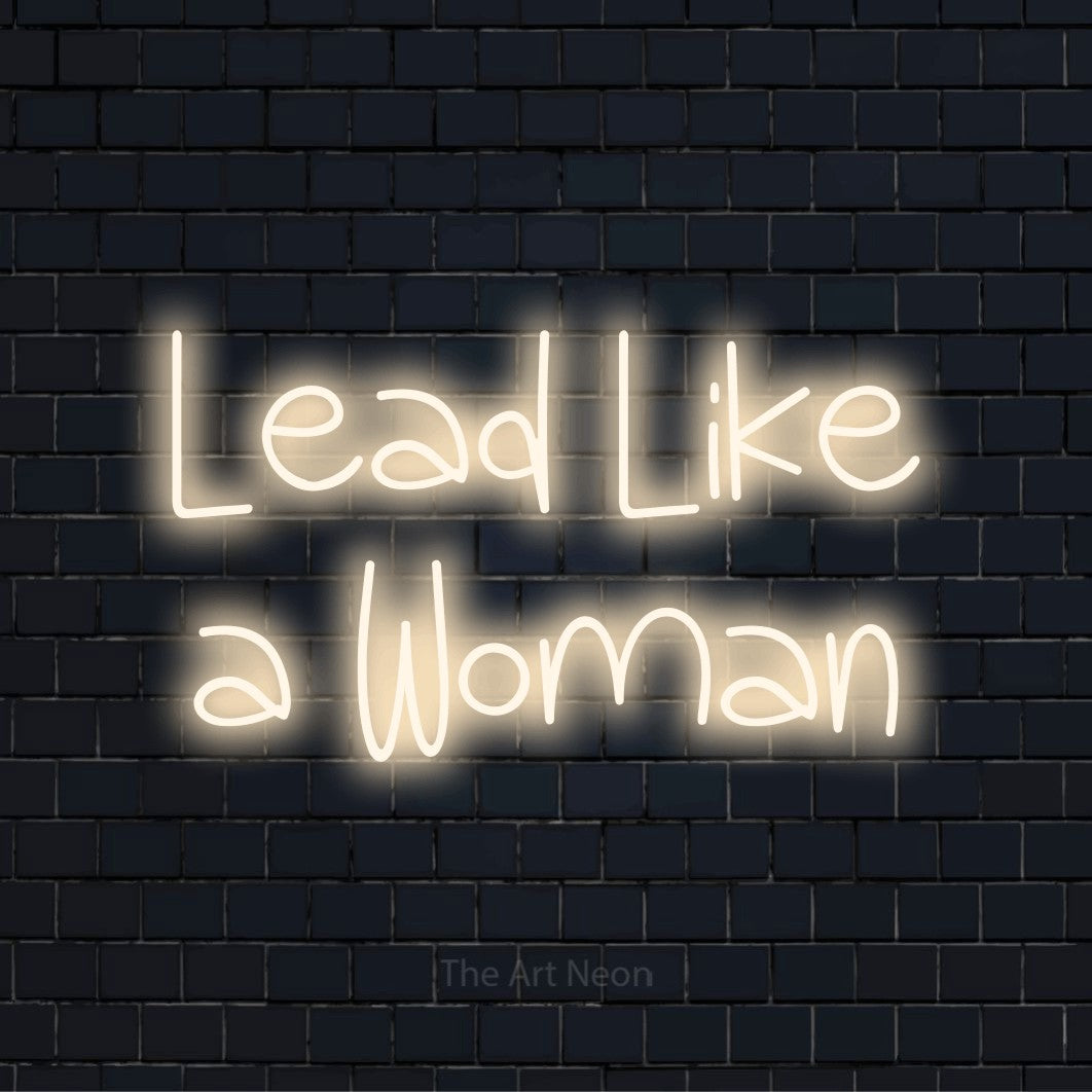 "Lead Like A Woman" glowing LED neon sign on a black brick wall
