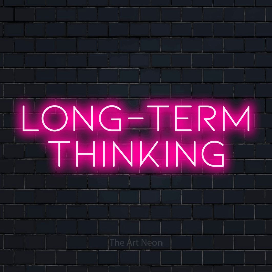 "Long-term Thinking" LED neon sign on a black brick wall
