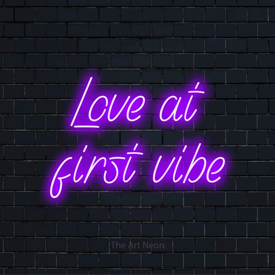 "Love At First Vibe" LED neon sign on a black brick wall