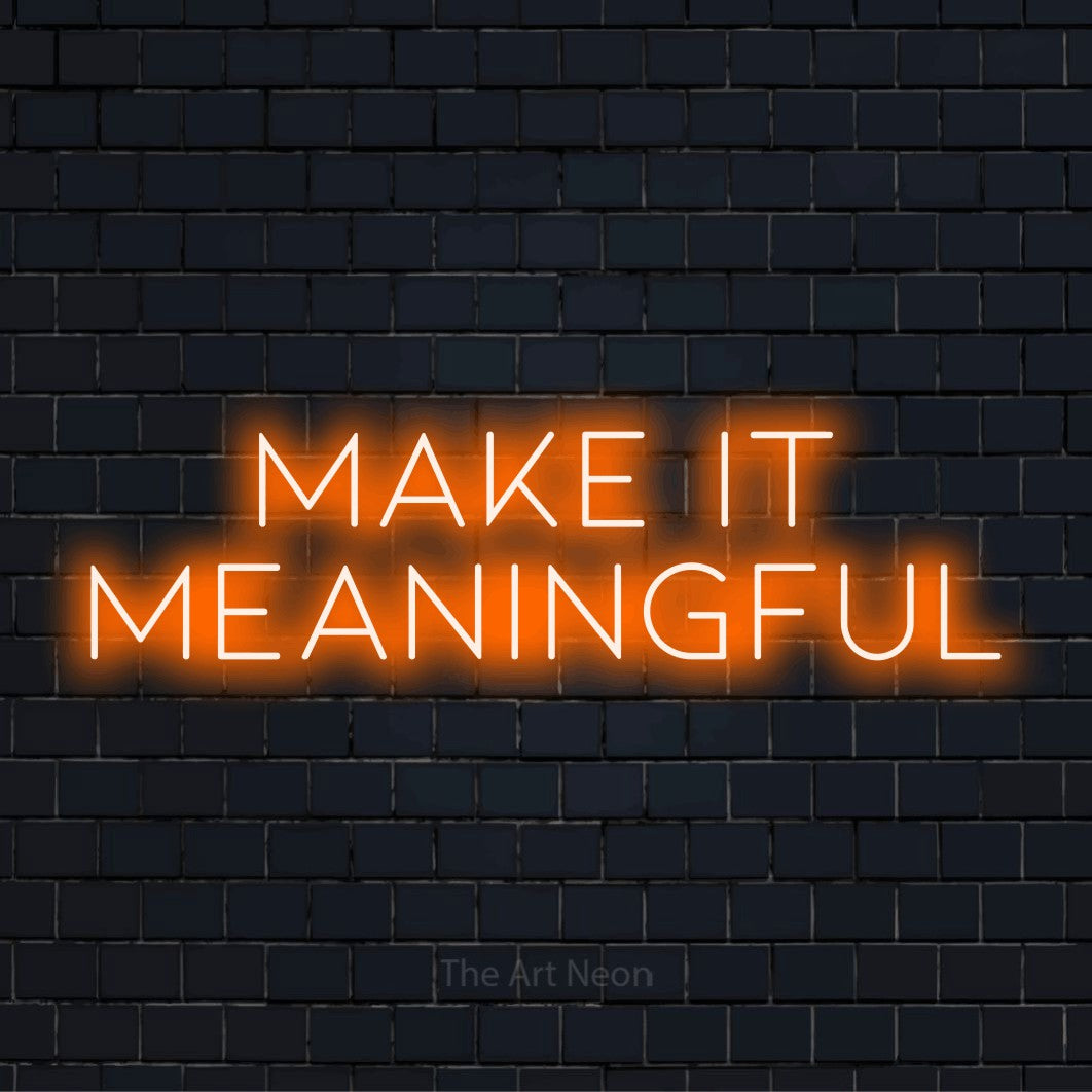 "Make It Meaningful" script-style LED neon sign on a black brick wall