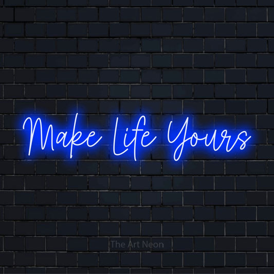 "Make Life Yours" script-style LED neon sign on a black brick wall