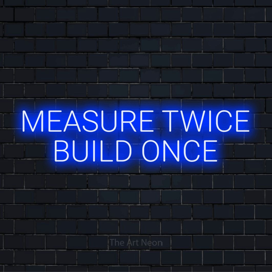 "Measure Twice Build Once" glowing LED neon sign on a black brick wall