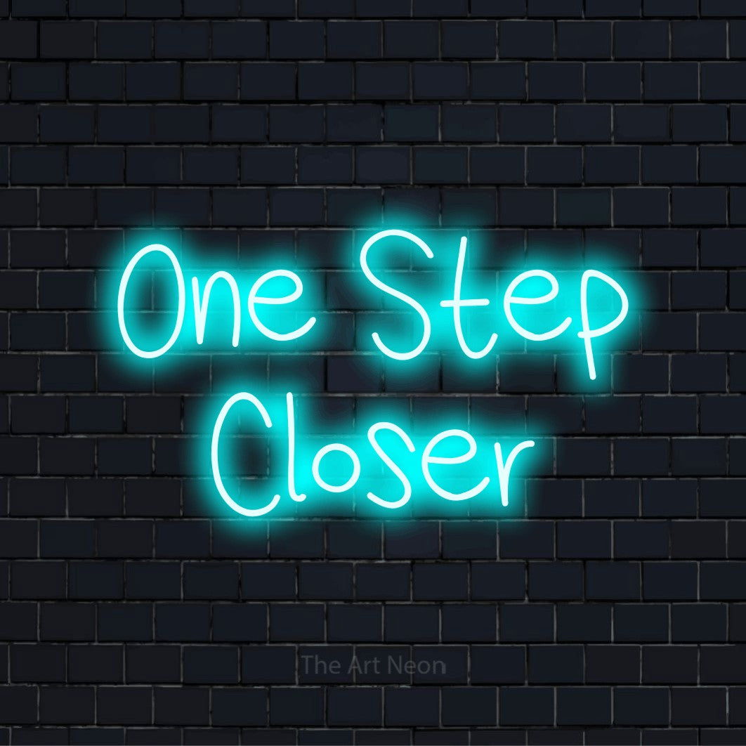 "One Step Closer" LED neon sign on a black brick wall