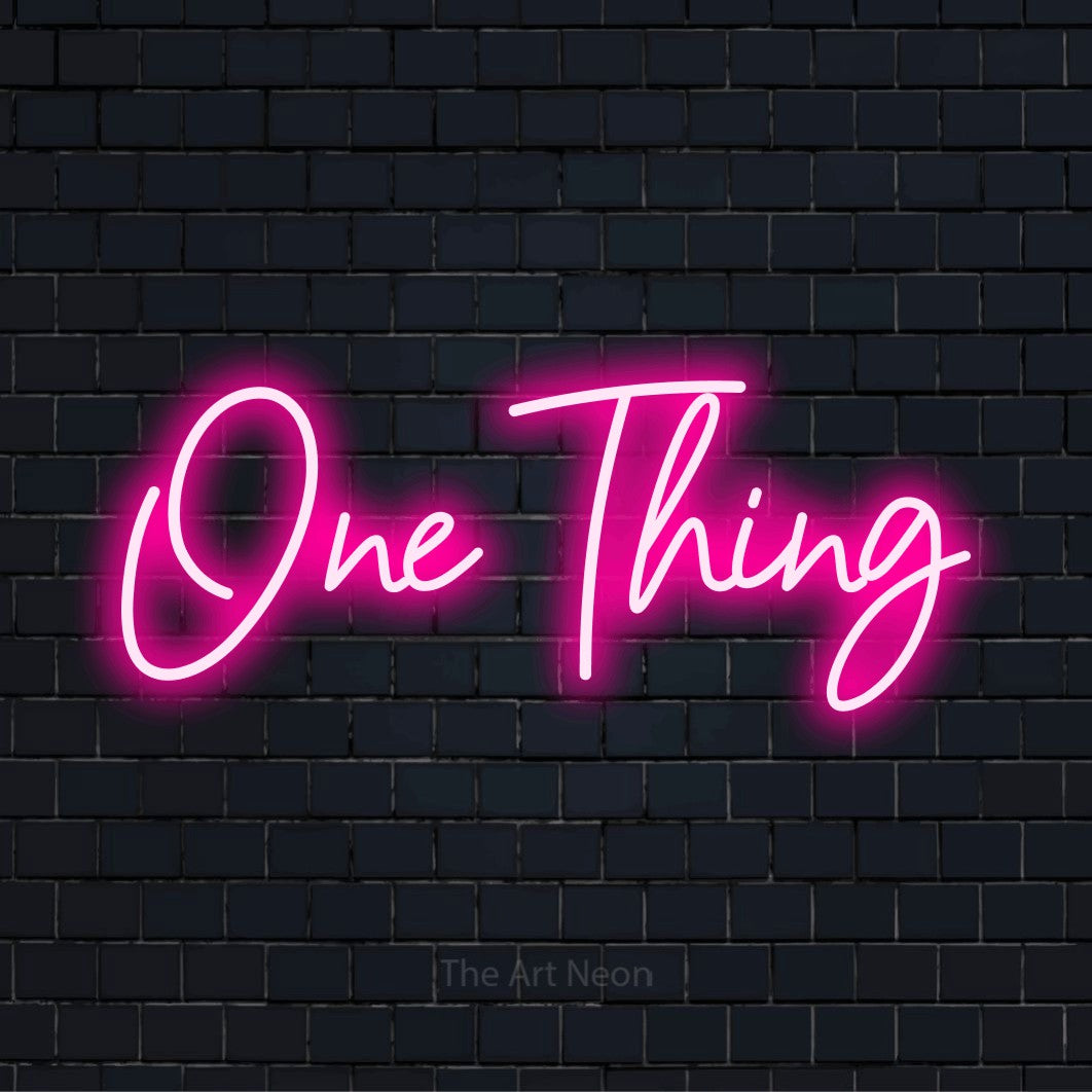 "One Thing" glowing LED neon sign on a black brick wall