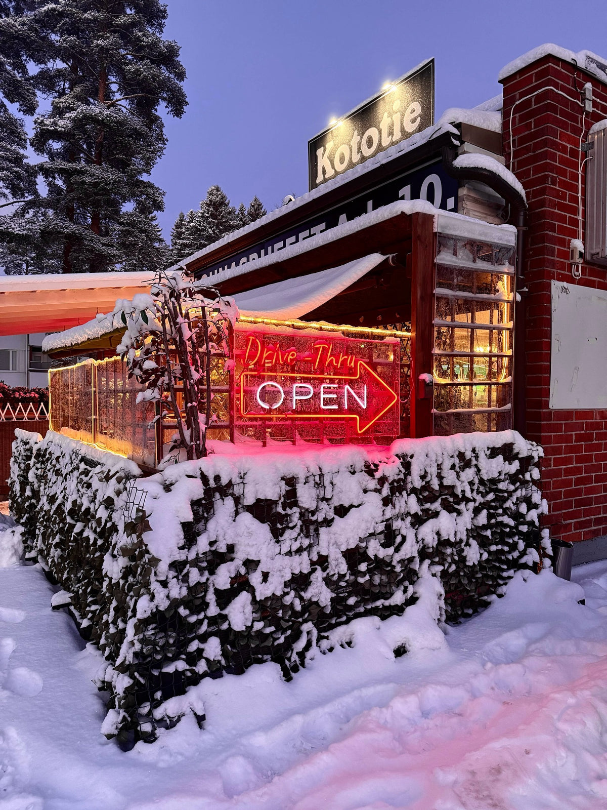 Rotes LED-Neonschild mit dem Schriftzug OPEN vor einem Restaurant bei Schnee