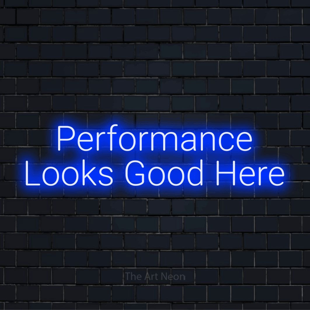 "Performance Looks Good Here" neon text design on a black brick wall