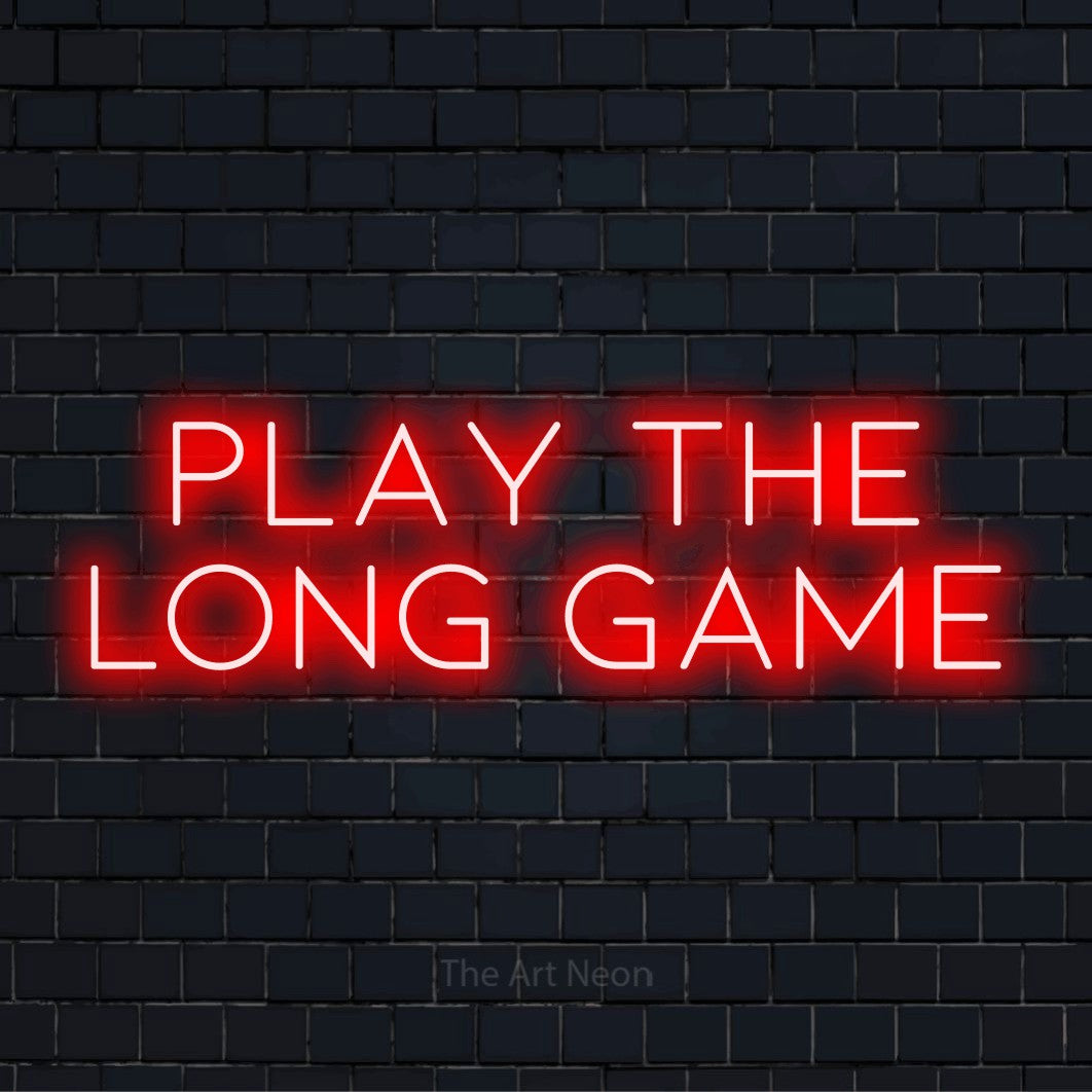"Play The Long Game" neon text design on a black brick wall