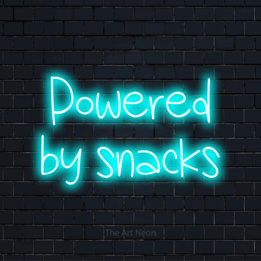 "Powered By Snacks" text design with neon effect on a black brick wall