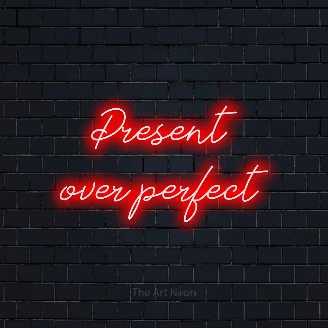 "Present Over Perfect" LED neon sign on a black brick wall