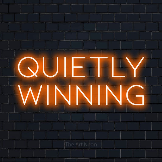 "Quietly Winning" neon text design on a black brick wall
