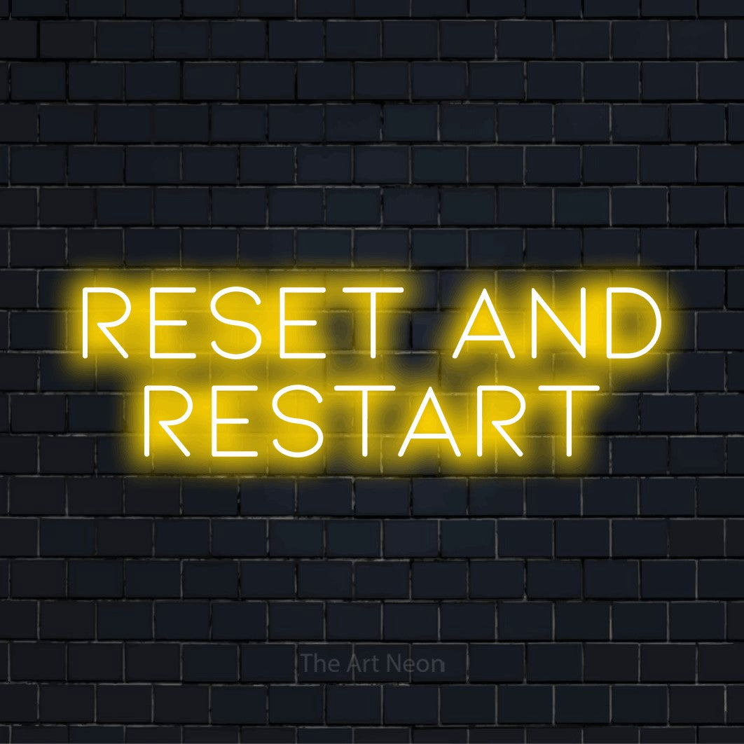 "Reset And Restart" glowing LED neon sign on a black brick wall