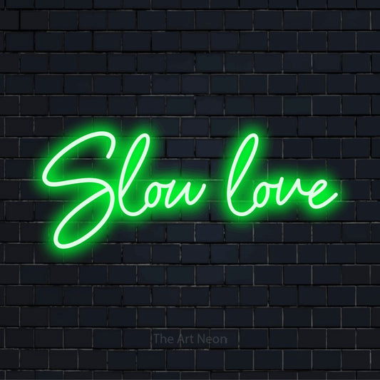 "Slow Love" text design with neon effect on a black brick wall