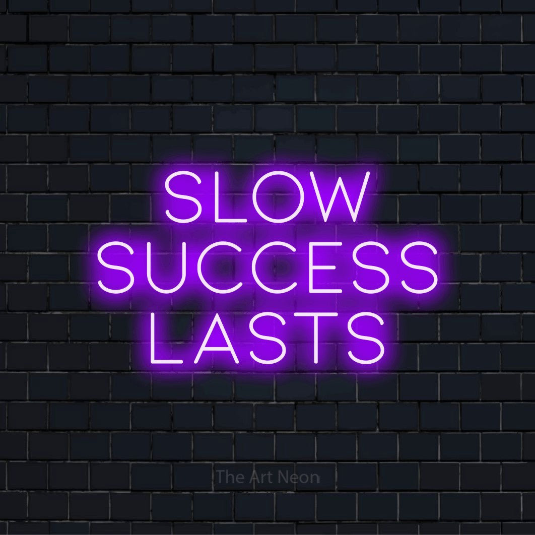 "Slow Success Lasts" LED neon sign on a black brick wall