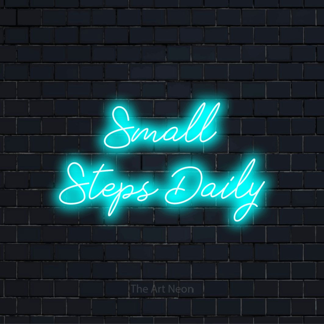 "Small Steps Daily" LED neon sign on a black brick wall