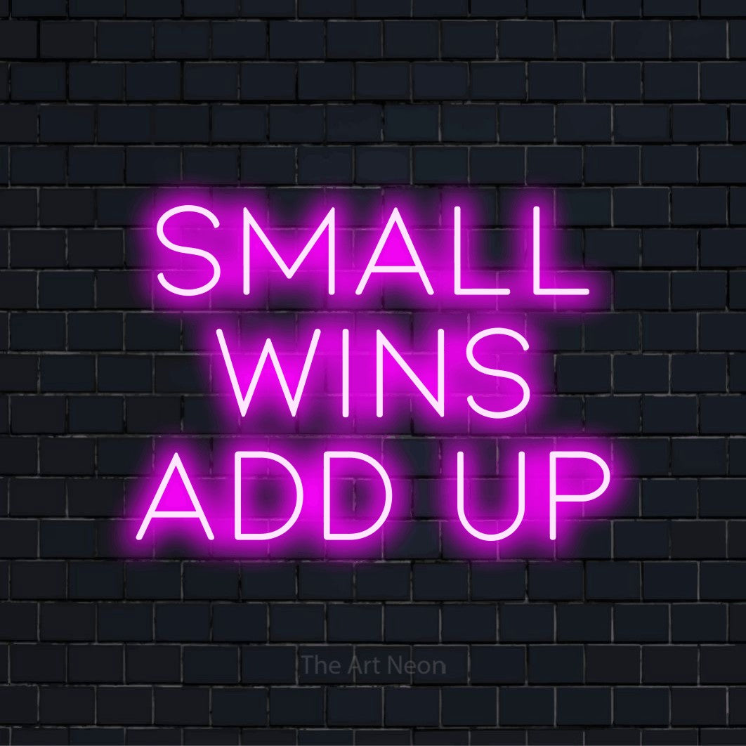 "Small Wins Add Up" glowing LED neon sign on a black brick wall