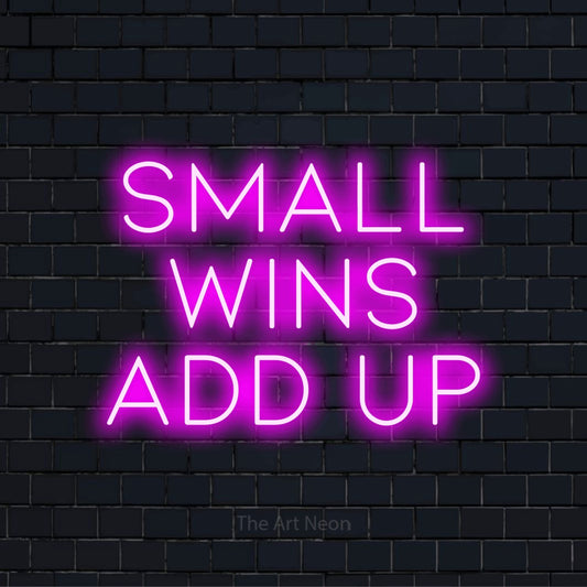 "Small Wins Add Up" glowing LED neon sign on a black brick wall
