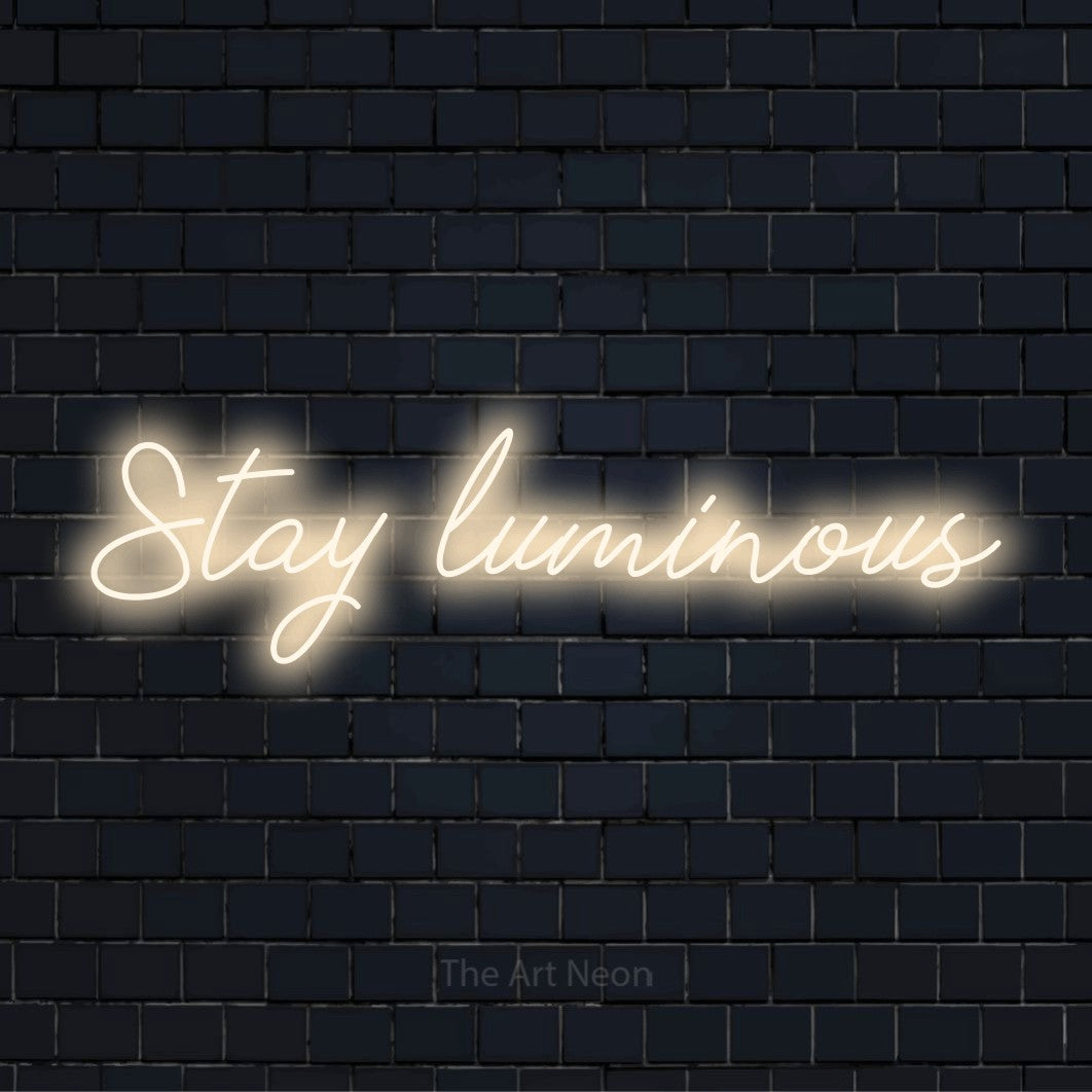"Stay Luminous" neon text design on a black brick wall