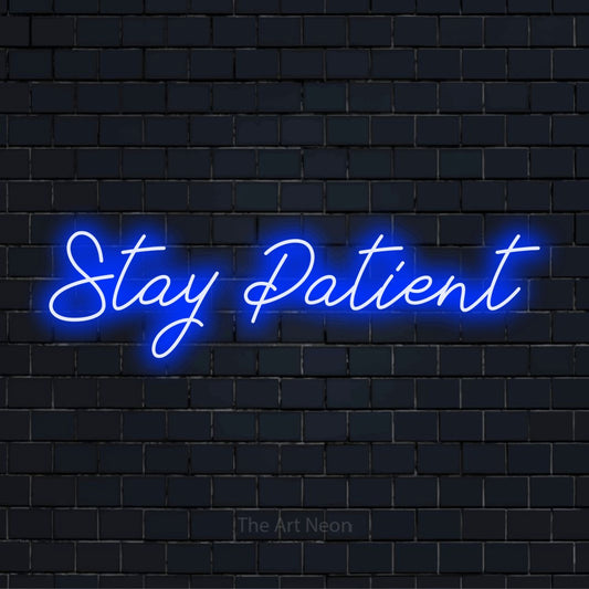 "Stay Patient" script-style LED neon sign on a black brick wall