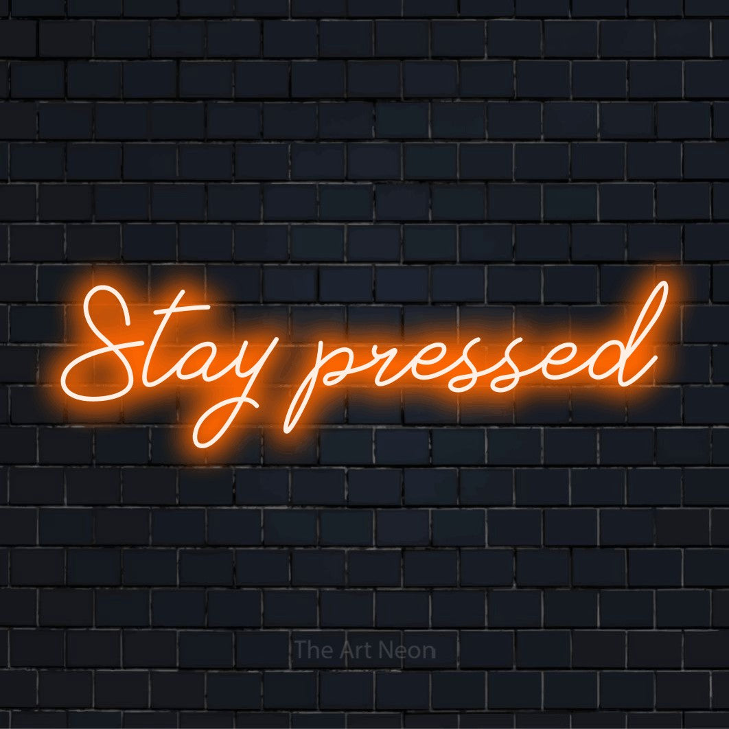 "Stay Pressed" glowing LED neon sign on a black brick wall