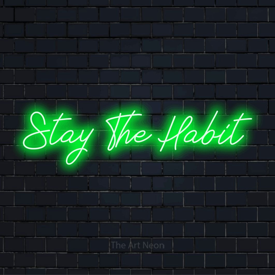 "Stay The Habit" glowing LED neon sign on a black brick wall