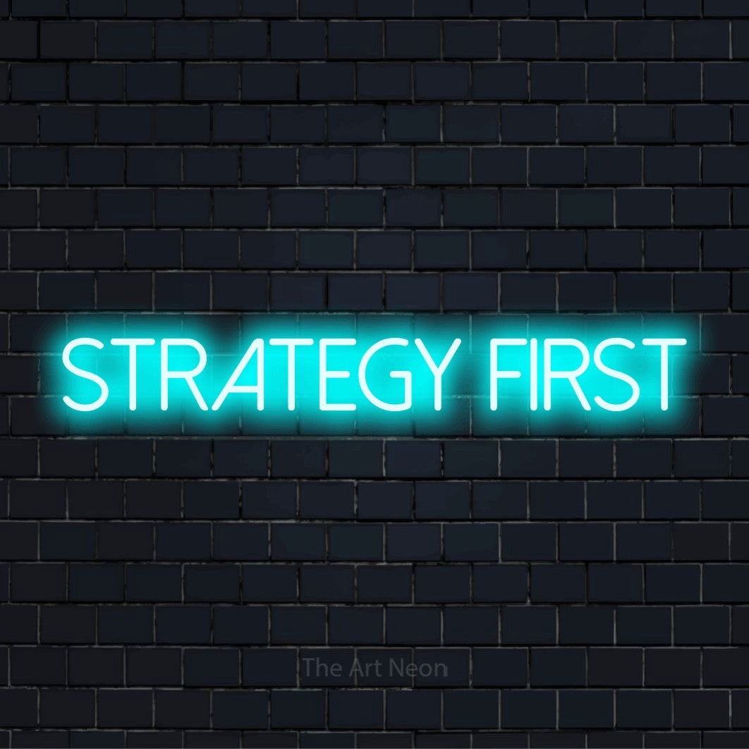 "Strategy First" script-style LED neon sign on a black brick wall