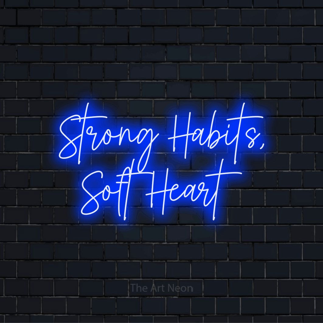 "Strong Habits, Soft Heart" LED neon sign on a black brick wall