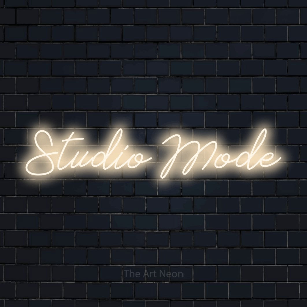 "Studio Mode" neon text design on a black brick wall