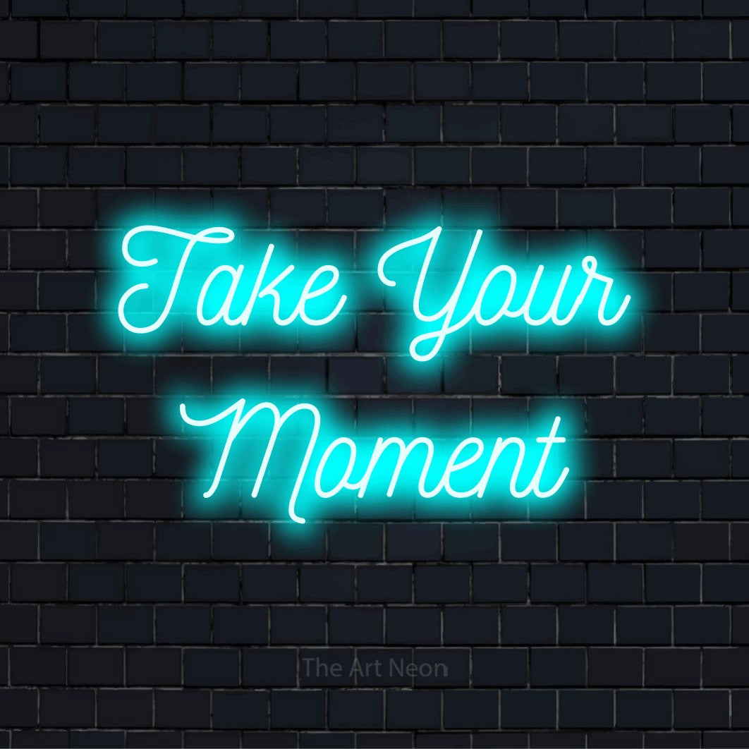 "Take Your Moment" text design with neon effect on a black brick wall
