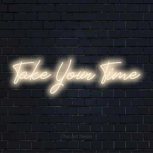 "Take Your Time" script-style LED neon sign on a black brick wall
