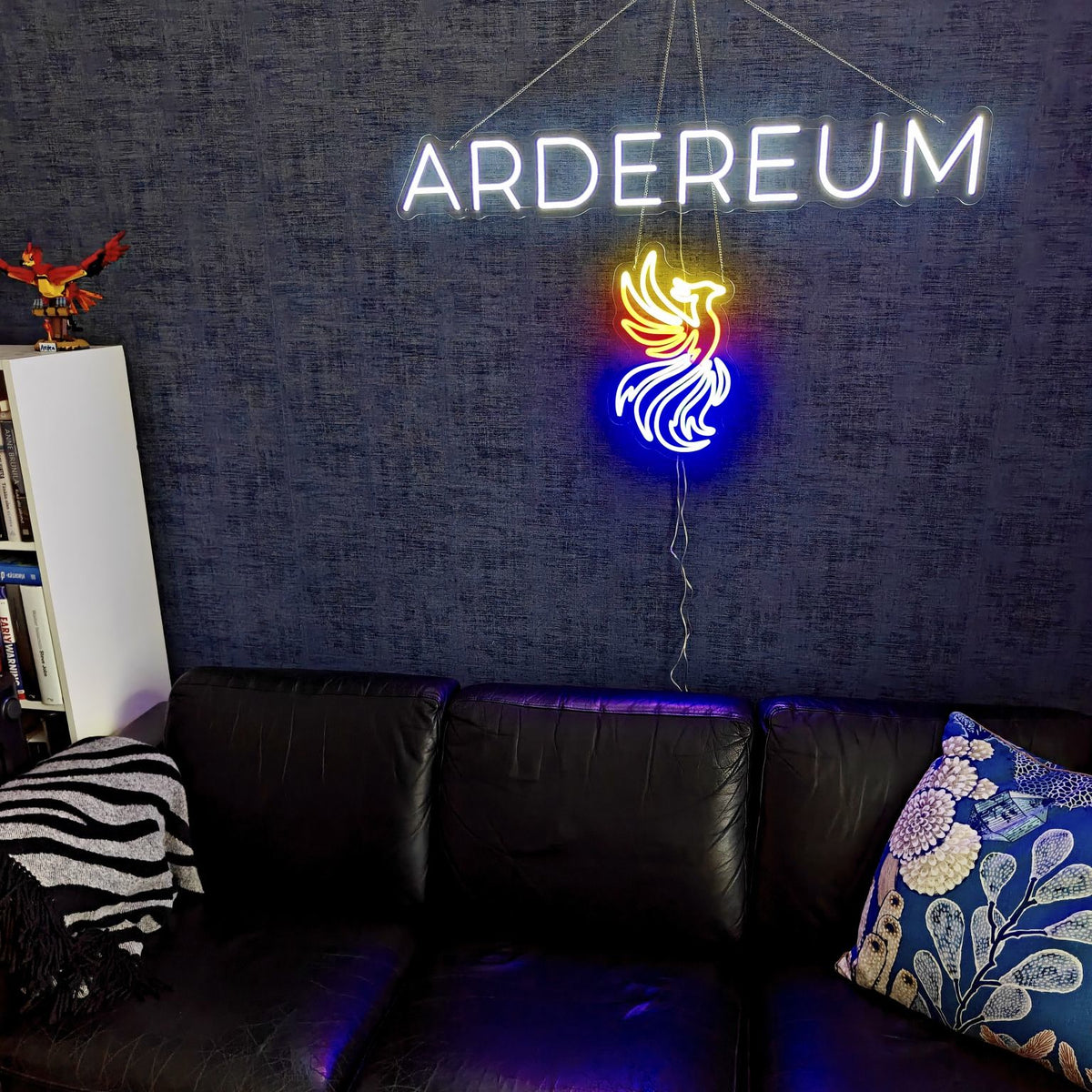 White ARDEREUM office logo LED neon installed on a dark textured wall.