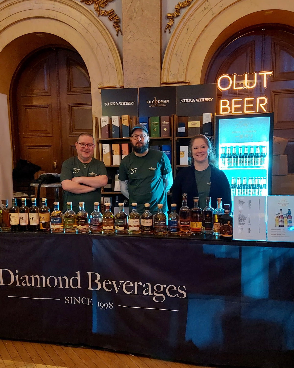 Warm leuchtender OLUT BEER-LED-Neonschriftzug über dem Verkostungsstand von Diamond Beverages.