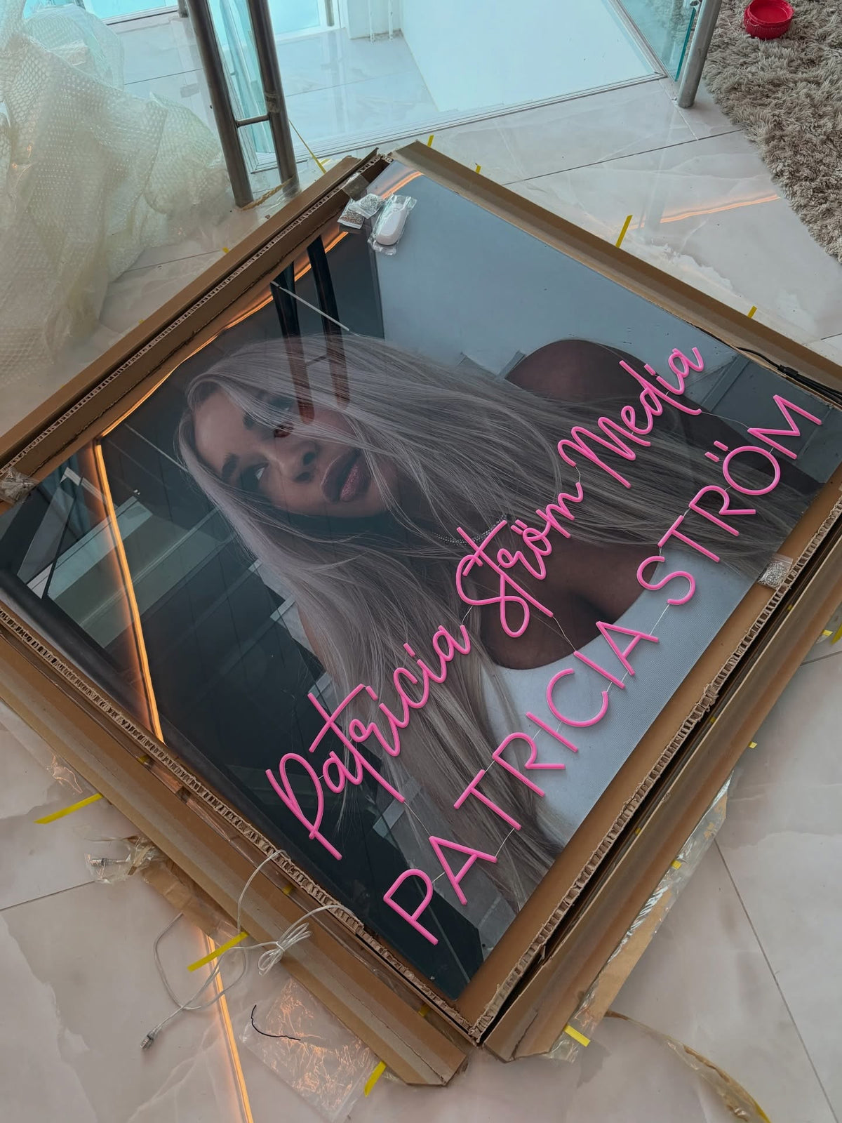 Pinkes Neonlogo von Patricia Ström Media neben Patricia Ström in ihrem markengerecht gestalteten Arbeitsraum