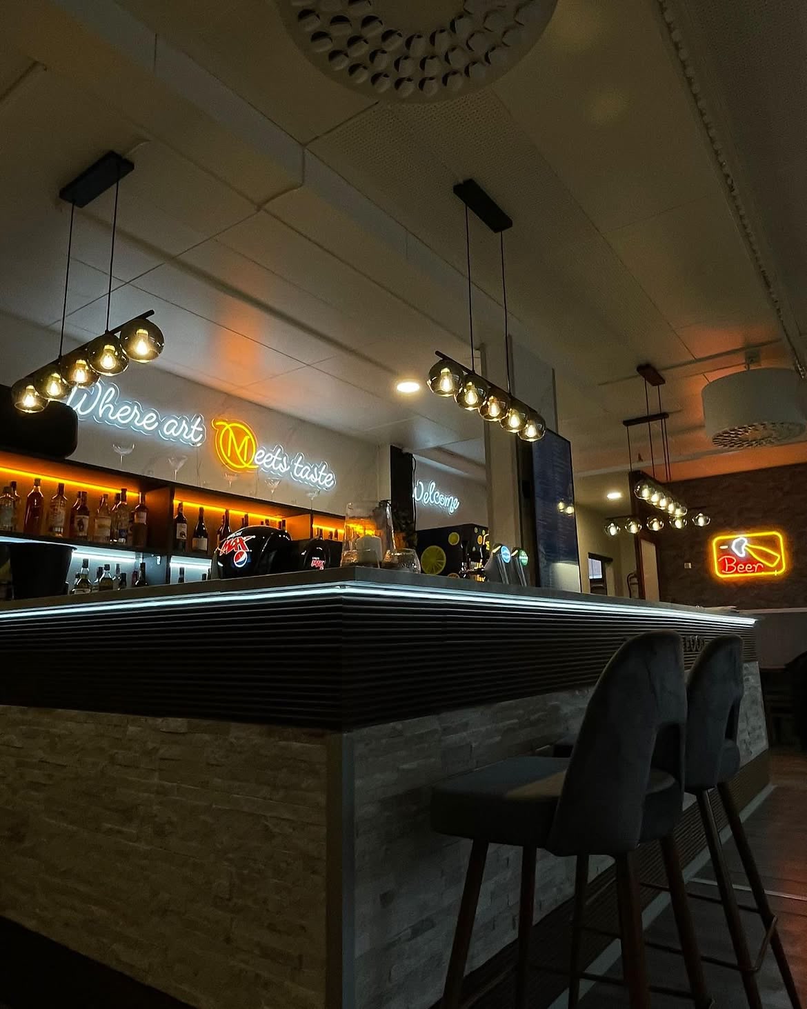Grünes LED-Neonschild für ein Restaurant über Sitznischen in einem farbenfrohen Gastraum