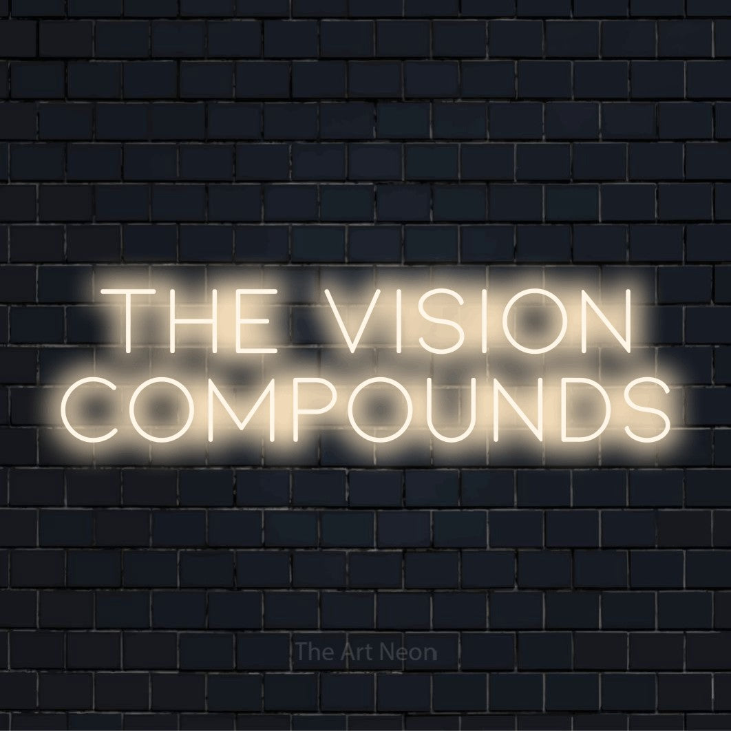 "The Vision Compounds" neon text design on a black brick wall