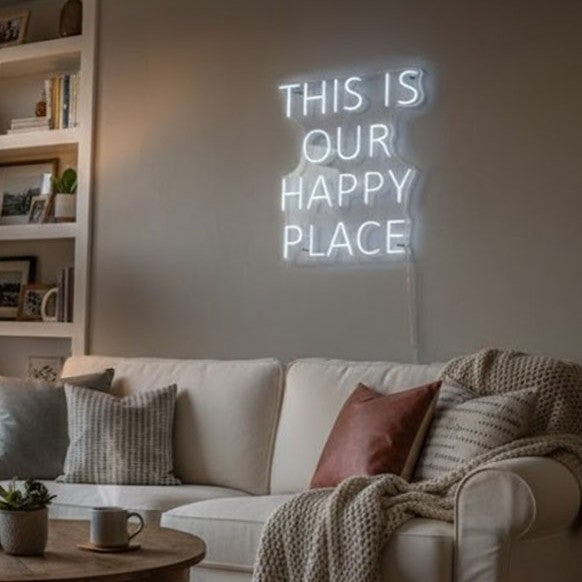 Weißes LED-Neonschild mit dem Schriftzug This Is Our Happy Place in einem eingerichteten Wohnzimmer