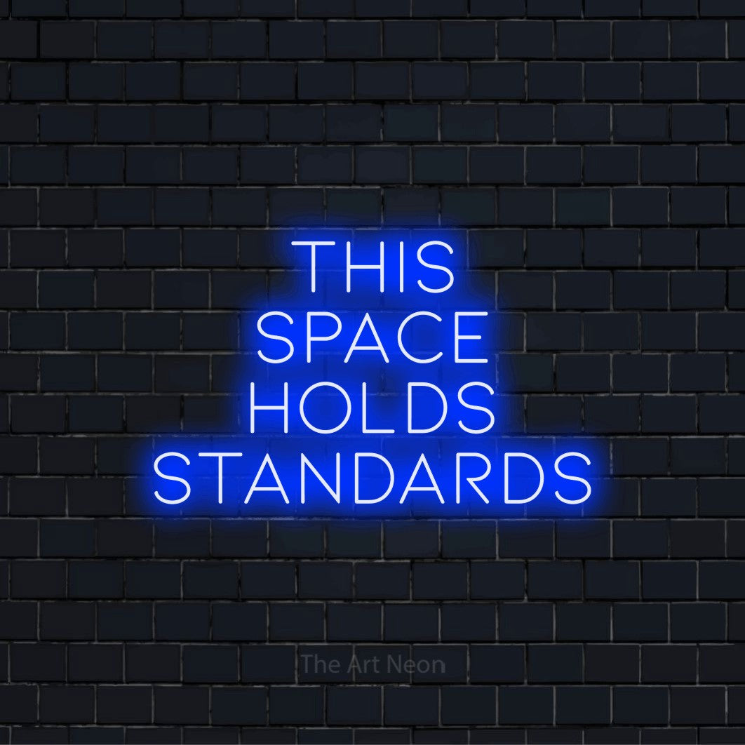 "This Space Holds Standards" glowing LED neon sign on a black brick wall